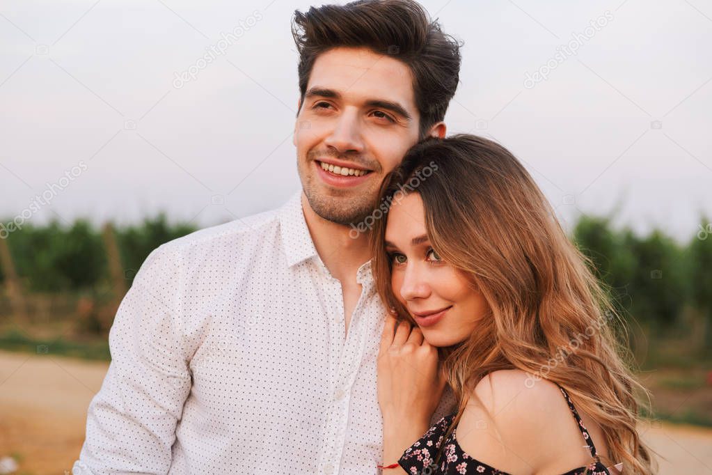 Picture of young happy cute loving couple outdoors hugging with each other.