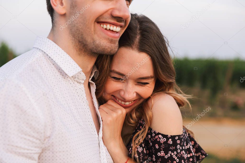 Picture of young happy cute loving couple outdoors hugging with each other.