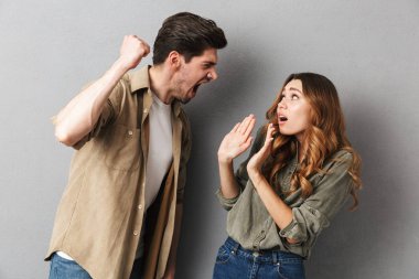 Mutsuz genç bir çift olan bir bağımsız değişken, öfkeli adam gri arka plan üzerinde izole kız bağırıyor