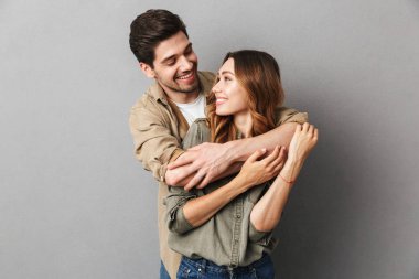 Portrait of a happy young couple hugging isolated over gray background clipart