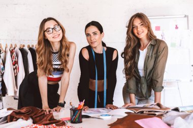 Üç mutlu genç kadın giyim tasarımcıları atelier birlikte çalışma