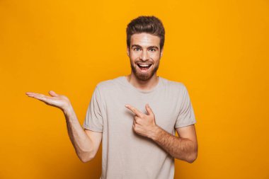 Yakışıklı adam sarı duvar backgroung işaret içinde izole ayakta görüntüsünü.