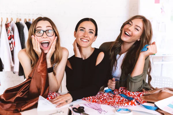Три Веселих Молодих Жінки Дизайнери Одягу Працюють Разом Ательє Сидячи — стокове фото