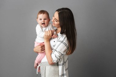 Gri arka plan üzerinde izole küçük çocuğu elinde tutan beyaz anne kadın portresi
