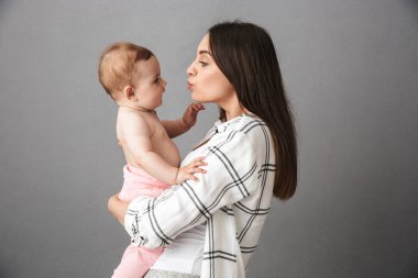 Küçük bebek kızı gri arka plan üzerinde tutan bir genç annelerin portresi