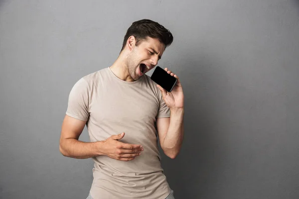 Retrato Joven Alegre Camiseta Aislado Sobre Fondo Gris Sosteniendo Pantalla — Foto de Stock