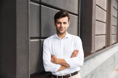 Açık havada duvara yaslanmış çekici genç erkek Yöneticisi resmi giyinmiş