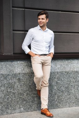 Mutlu genç erkek Yöneticisi resmi duvar açık havada eğilerek giyinmiş