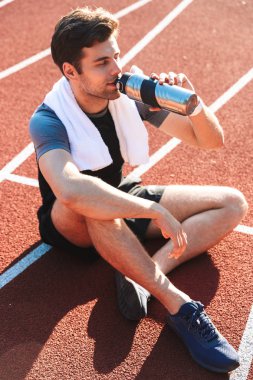 Yorgun sporcu Stadyumu'nda, dinlenme, bir su şişeden içme çalıştıran bitmiş