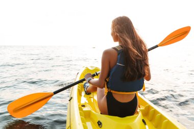 Genç kadının üzerinde botla göl denize Kayak fotoğrafını arkadan görünüm.