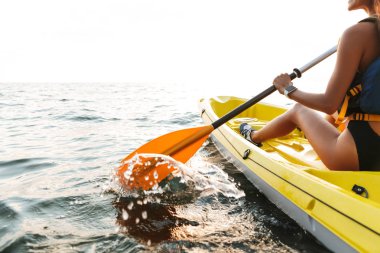 Genç kadının üzerinde botla göl denize Kayak fotoğrafını kırpılmış.
