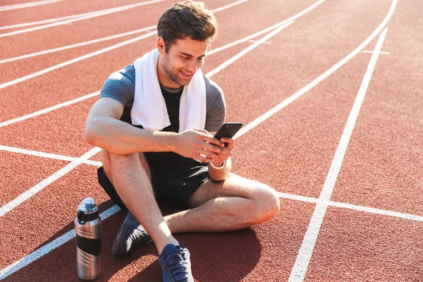 Gülümseyen sporcu istirahat, cep telefonuyla stadyumda çalıştıran bitmiş