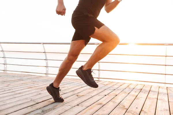 腿特写的肌肉运动的人20S 在运动服运行沿码头或在海边的木板路在早晨 — 图库照片