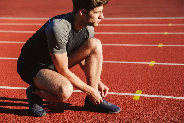 Giovane Sportivo Concentrato Che Lega Lacci Delle Scarpe Allo Stadio — Foto Stock