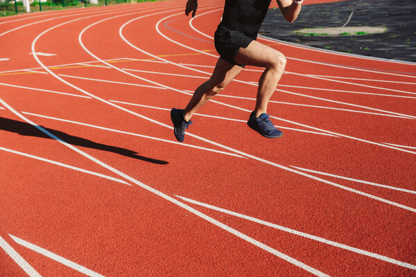 Cropped image of motivated young sportsman running at the stadium