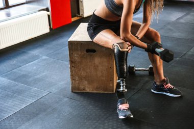Protez, eğitim ve spor salonunda halter kaldırma eşofman giyen genç Engelli geçersiz kadın portresi