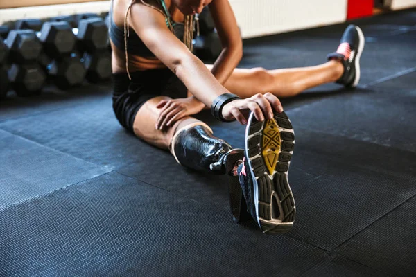 Cropped image of strong disabled sports woman make sport stretching exercises in gym.