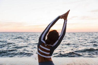 Kumsalda yoga egzersizleri yapıyor genç bir kadın portresi arkadan görünüm