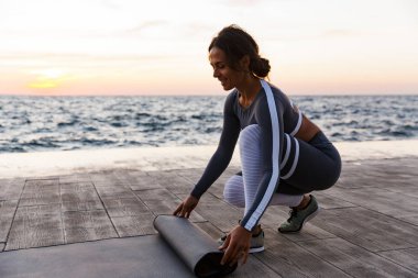 Plajda bir gülümseyen genç kadın unrolling fitness mat portresi