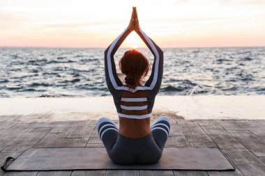 Arkadan görünüm fotoğraf plaja kadında açık havada güçlü genç fitness egzersizleri meditasyon yoga olun.