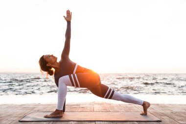 İnanılmaz güçlü genç fitness kadın açık havada Beach'teki görüntüsünü oluşturmak germe egzersizleri yoga.