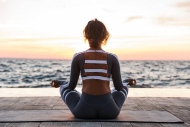 Arkadan görünüm fotoğraf plaja kadında açık havada güçlü genç fitness egzersizleri meditasyon yoga olun.
