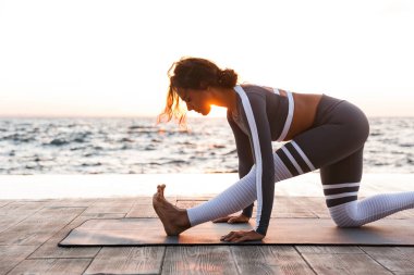 İnanılmaz güçlü genç fitness kadın açık havada Beach'teki görüntüsünü oluşturmak germe egzersizleri yoga.