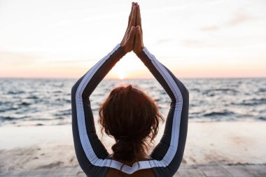 Arkadan görünüm fotoğraf plaja kadında açık havada güçlü genç fitness egzersizleri meditasyon yoga olun.