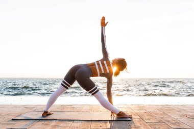 İnanılmaz güçlü genç fitness kadın açık havada Beach'teki görüntüsünü oluşturmak germe egzersizleri yoga.