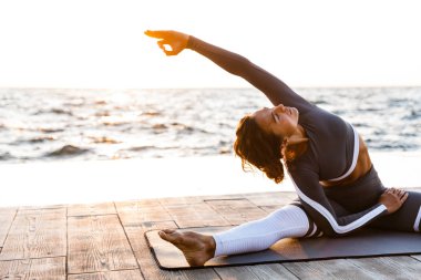 İnanılmaz güçlü genç fitness kadın açık havada Beach'teki görüntüsünü oluşturmak germe egzersizleri yoga.