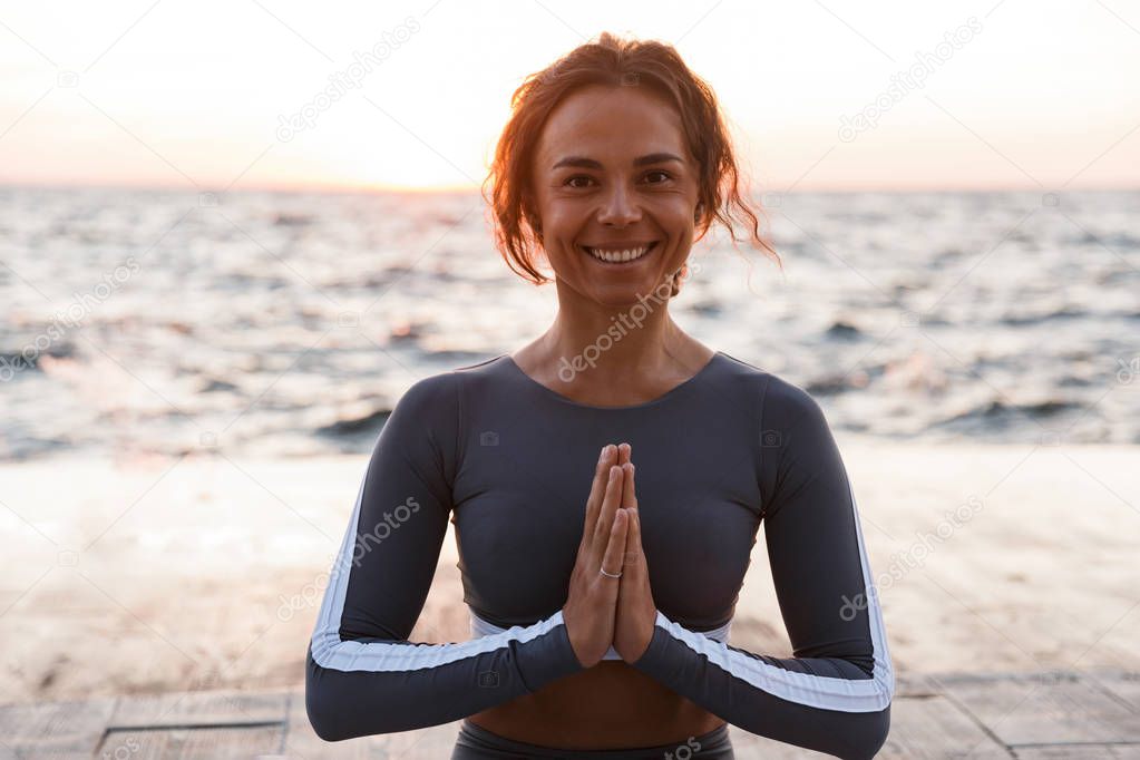 Image of happy cute strong young fitness woman outdoors in the beach make yoga meditate exercises.