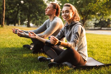 Görüntü konsantre Fitness egzersizleri meditasyon park açık havada dost sevgi dolu çift spor. Neşeli kadın görünümlü kamera.