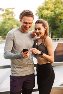 Görüntü mutlu fitness spor park açık havada dinleme müzik kulaklık ile seven çift arkadaşlar.