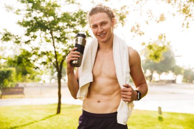 Güneşli yaz gününde Park eğitimleri sırasında fitness vücut 20'li yaşlarda ayakta su ve havlu ile Avrupa sportif adam fotoğrafı