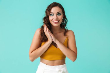 Gülümseyen ve mavi arka plan üzerinde bir kenara izole seyir küpeler güzel saç modeli ile 20'li yaşlarda genç ve güzel kadın fotoğrafı