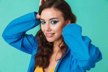 Beyaz güzel kadın 20'li yaşlarda giyen yağmurluk ya da gülümseyerek ve mavi arka plan üzerinde izole baş, el ele tutuşarak ceket görüntü