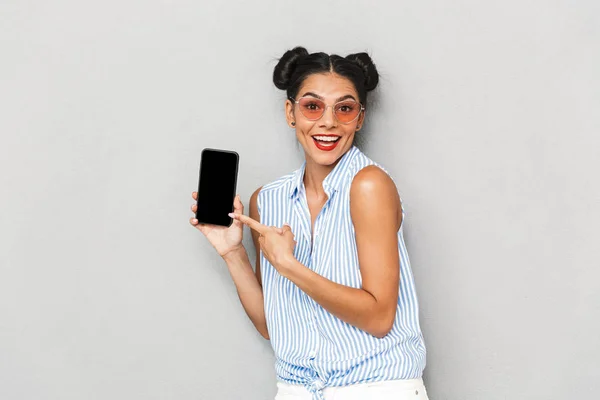 照片中的一个快乐的年轻女子在太阳镜隔离 显示空白屏幕移动电话 — 图库照片