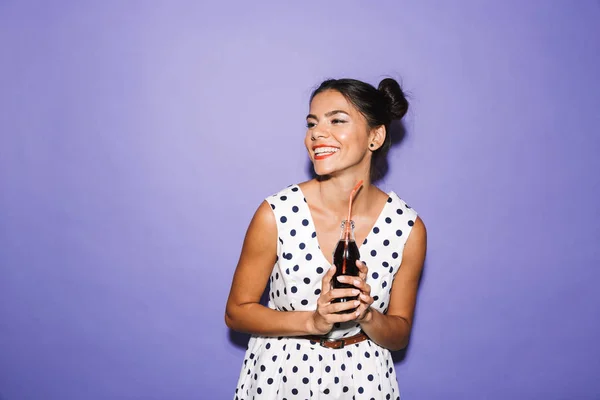 一个快乐的年轻女子的肖像在夏季礼服隔离 持有瓶碳酸饮料 看着复制空间 — 图库照片