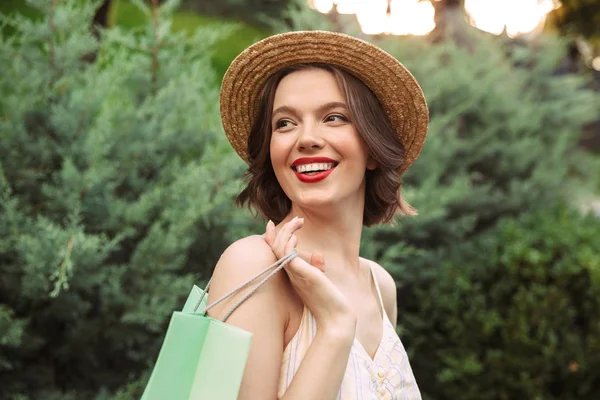Χαμογελαστή Γυναίκα Στο Φόρεμα Και Ψάθινο Καπέλο Που Ποζάρει Πακέτα — Φωτογραφία Αρχείου
