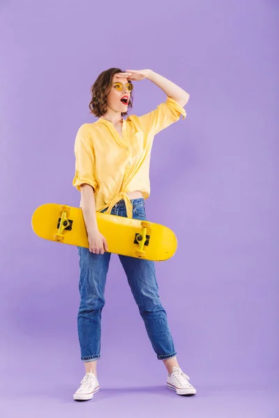 Портрет Веселої Молодої Дівчини Тримає Скейтборд Виділяється Фіолетовому Фоні Дивлячись — стокове фото
