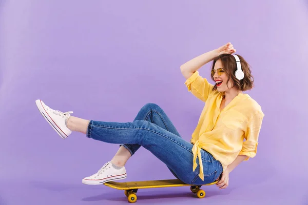 Retrato Una Joven Feliz Con Auriculares Sentados Monopatín Aislados Sobre —  Fotos de Stock