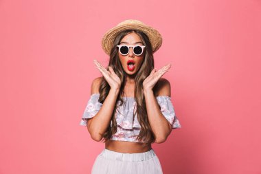 Kamera pembe bir arka plan üzerinde seyir yaz giysileri heyecanlı bir genç kız portresi