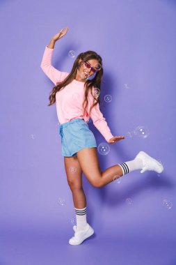 Studio violet arka plan üzerinde tam uzunlukta iki ponytails ise kazak gülen ve having fun ile genç ve güzel kadın portresi izole