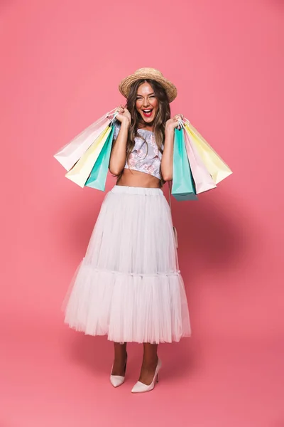 购物狂女人的全长图像20S 戴着草帽和蓬松的裙子微笑着拿着五颜六色的纸购物袋 上面是粉红色背景 — 图库照片