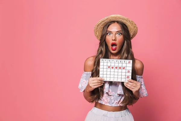 一个失望的愤怒的女人的肖像20S 戴草帽持有期间日历在工作室粉红色背景隔离 — 图库照片