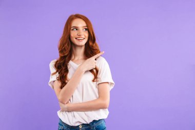 Kopya alanı işaret menekşe arka plan üzerinde izole bir gülümseyen genç kız ayakta portresi