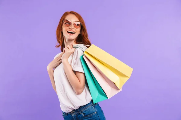 一个开朗的年轻女孩的肖像站在紫罗兰色背景隔离 背着购物袋 看着远离 — 图库照片