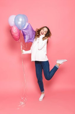 Hava balonları demet atlama üzerinde pembe arka plan izole tutarken hoş bir genç kadın portresi tam uzunlukta