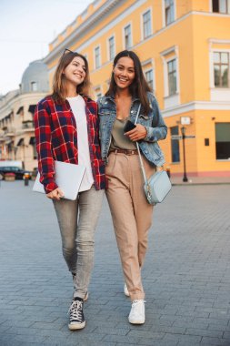 Birlikte şehir street yürüyüş, dizüstü holding, konuşmak iki genç ve güzel kız arkadaş