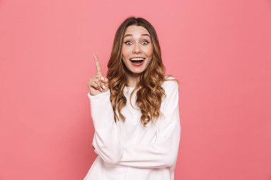 Heyecanlı bir genç casual kız pembe arka plan üzerinde izole kopya alanı işaret portresi